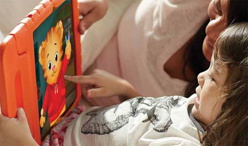 Mom and daughter play Daniel Tiger game on notebook computer.